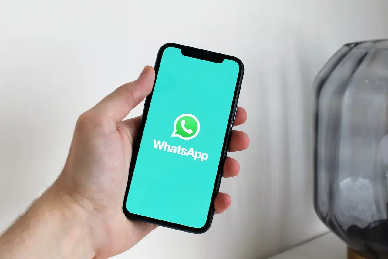 Mão segurando celular com tela do Whatsapp
