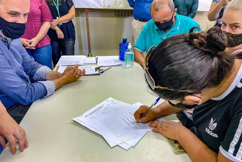Imagem de famílias assinando contrato de recebimento do bônus-moradia.