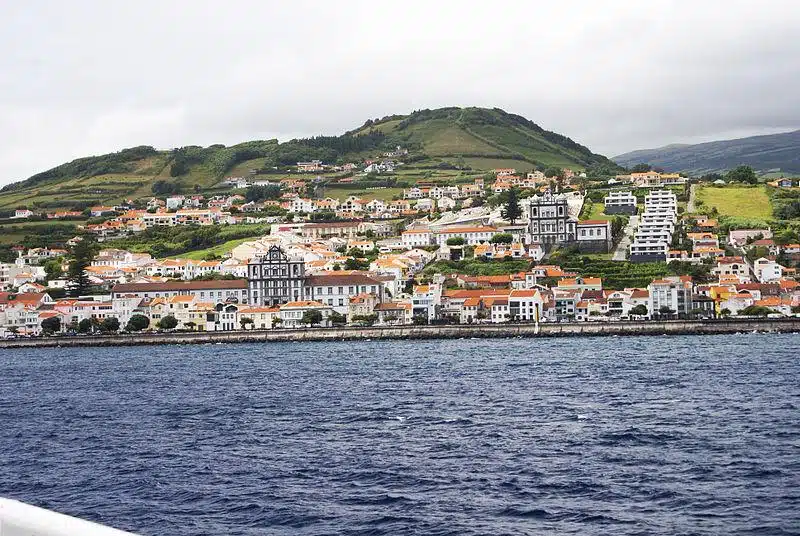 Foto da Cidade da Horta vista da Baía da Horta, ilha do Faial, Açores, Portugal. Mostra uma paisagem urbana em frente á água, representando um dos destinos para viagens internacionais.
