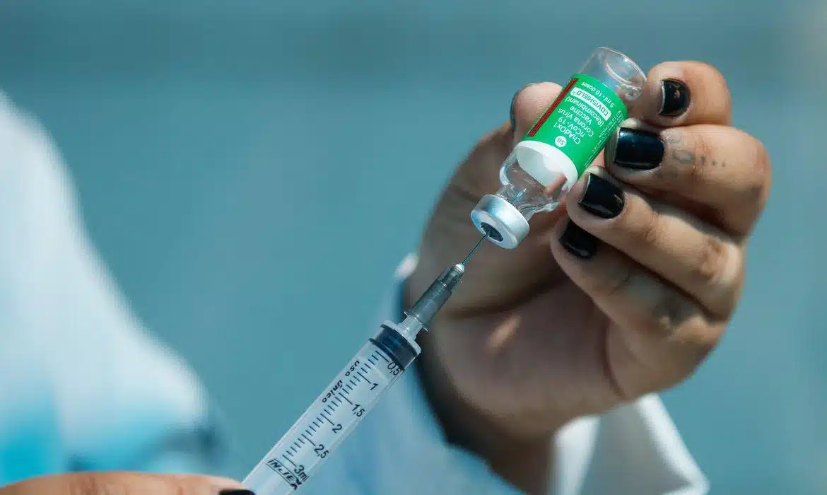 Foto mostra profissional preparando seringa com dose de vacina.