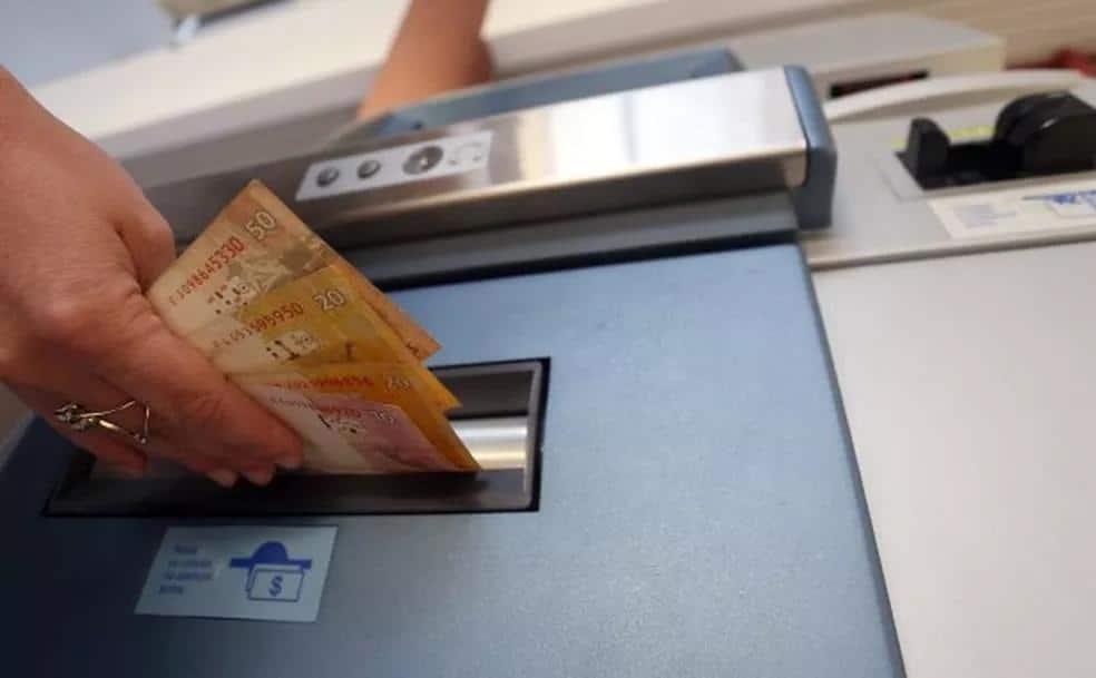 Foto mostra pessoa sacando dinheiro em terminal de atendimento. A imagem é ilustrativa do saque dos valores liberados para beneficiários do INSS.