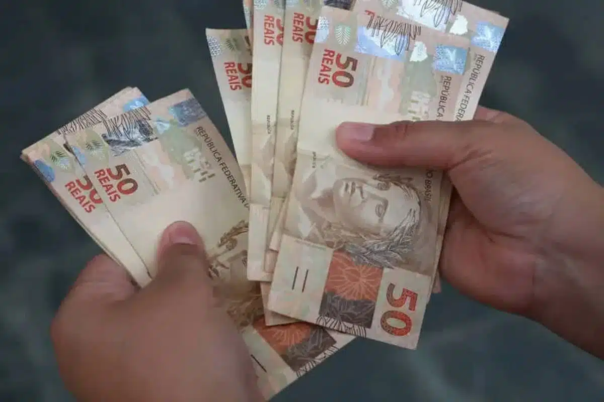 Pessoa segurando notas de 50 reais.