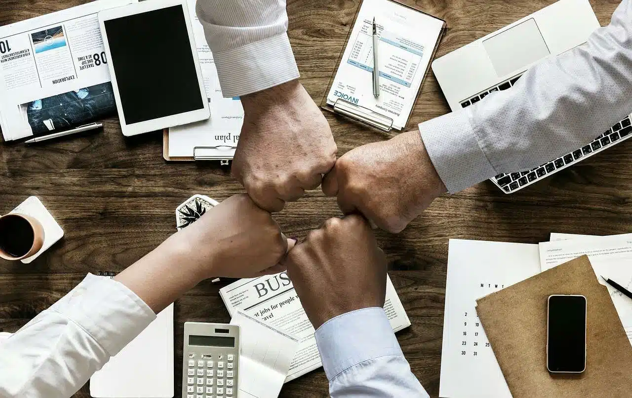 Foto mostra pessoas com as mãos juntas, em um sinal de trabalho em equipe. Busca ilustrar as marcas com bons ambientes de trabalho.
