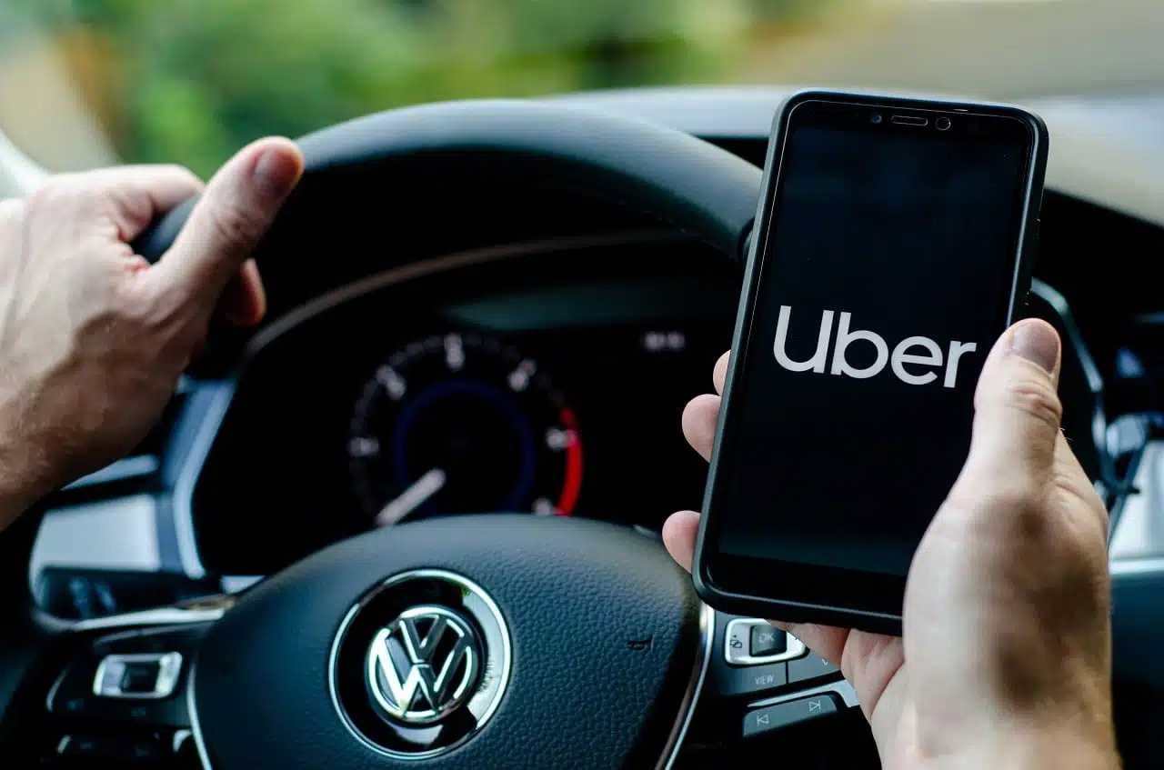 Na foto, um motorista segurando um celular com o app do uber aberto