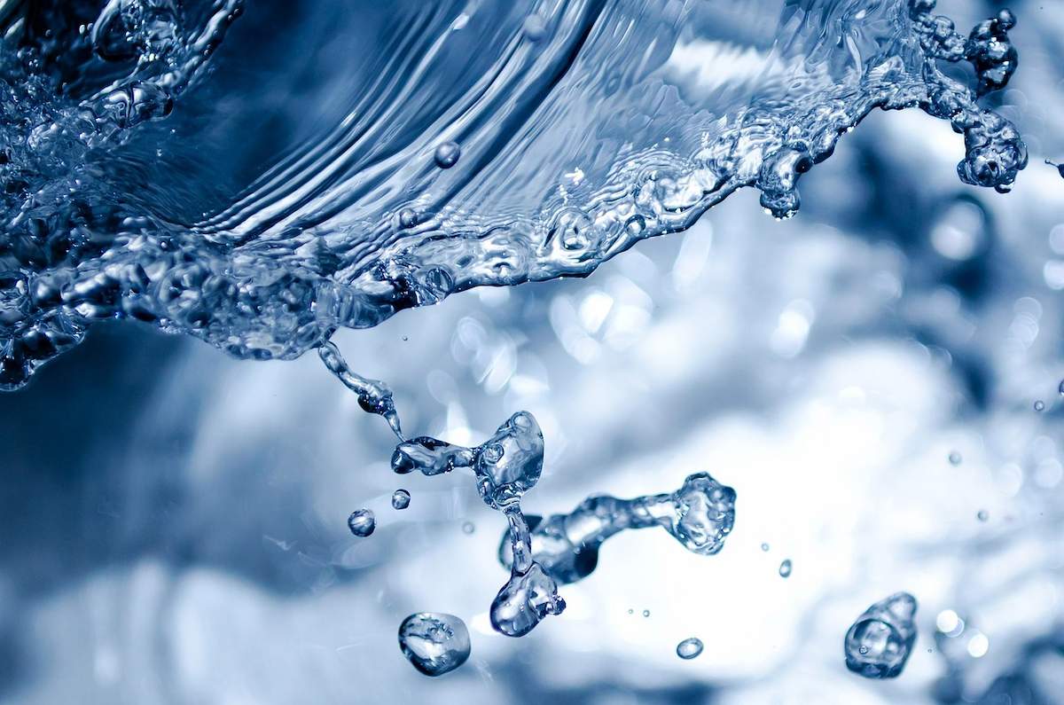 A imagem mostra uma representação aproximada de água, com gotículas espirrando em direção à foto.