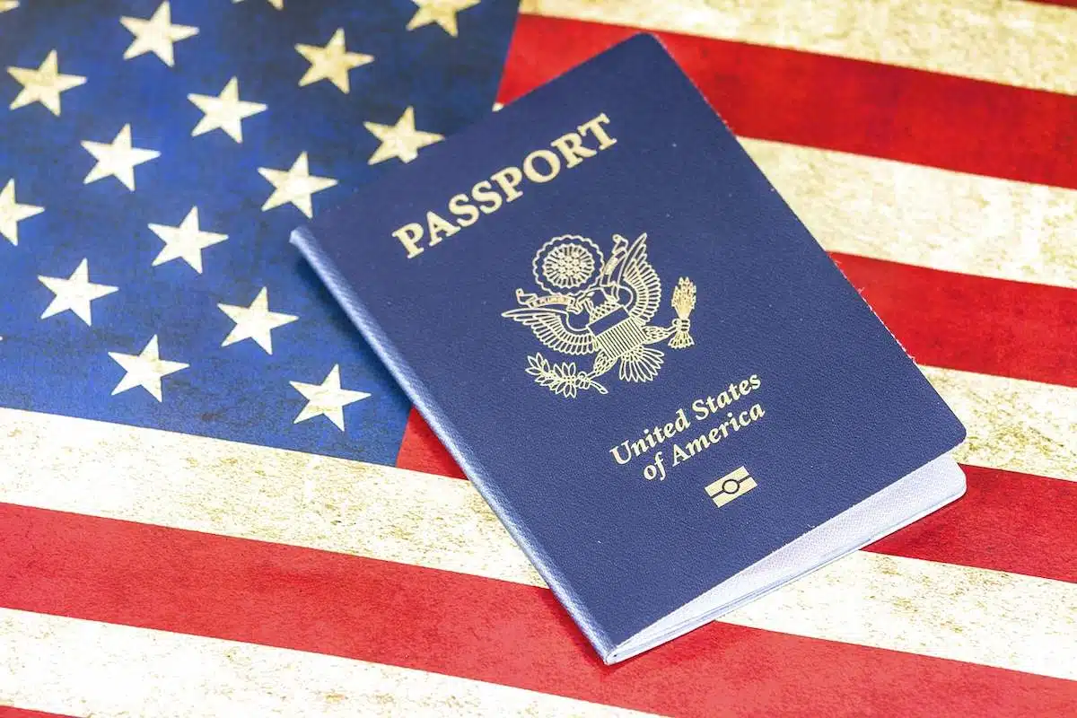 Foto mostra passaporte acima de uma bandeira dos EUA.