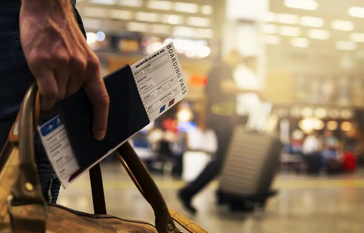Foto mostra pessoa em aeroporto com passaporte na mão. Imagem ilustrativa das viagens para a cidade de SC onde será sediado o festival.