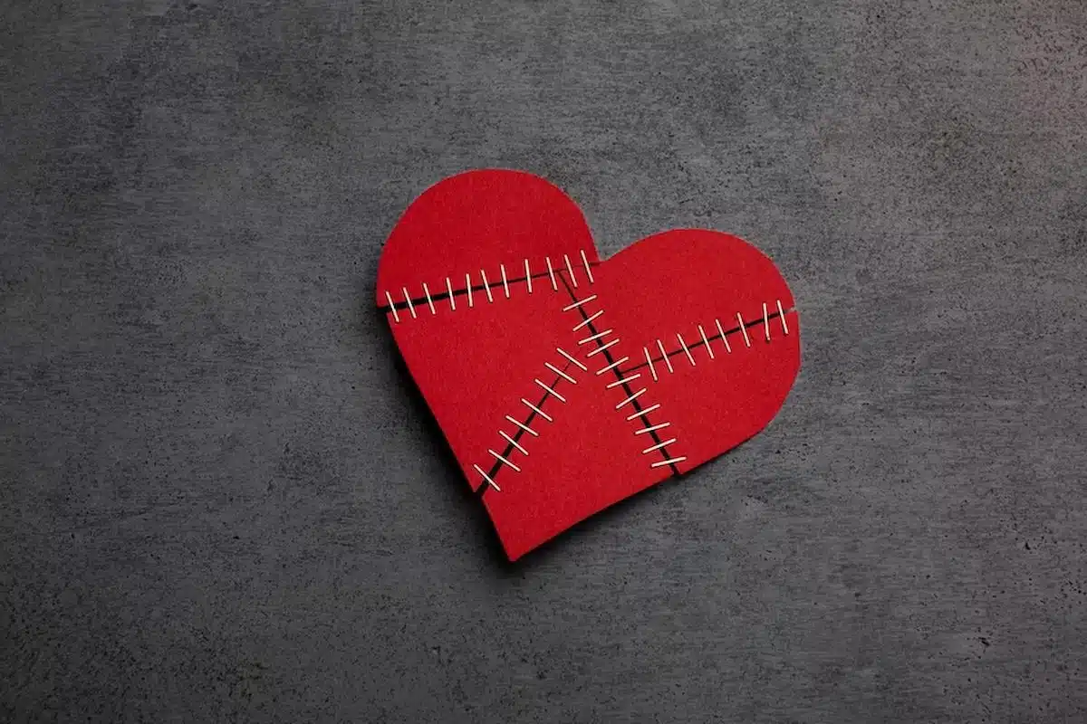 Foto mostra um papel em formato de coração, com cortes remendados. Imagem ilustrativa de uma traição.
