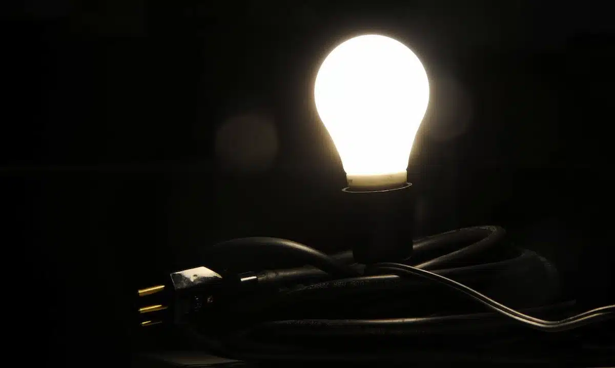 Foto mostra uma lâmpada acesa, emitindo luz em uma área escura.