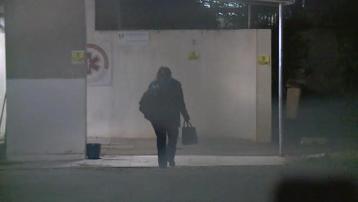 Foto mostra uma mulher, segurando uma sacola, andando em uma unidade do SAMU.