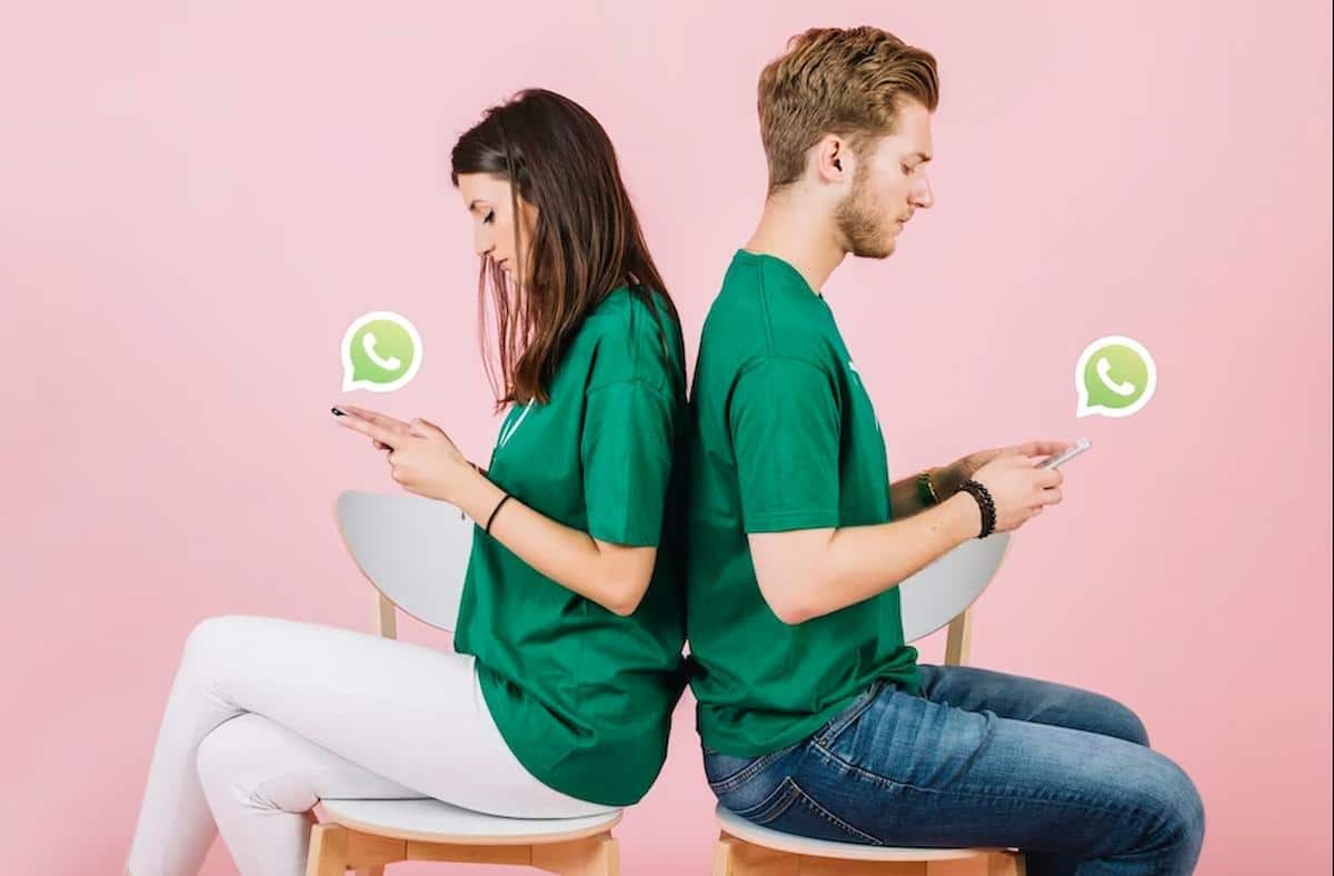 Foto mostra casal virado de costas, cada um segurando um celular, trocando mensagens no WhatsApp.