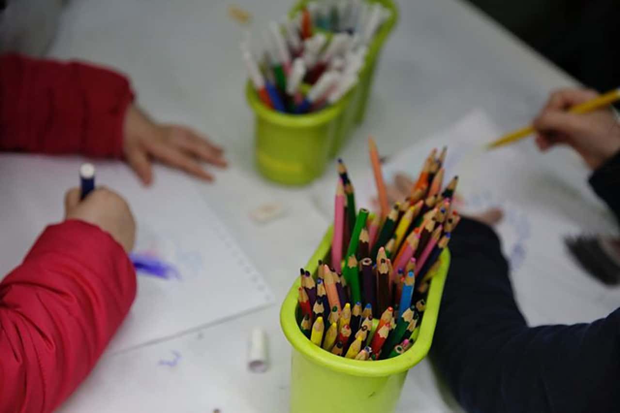 Lápis de cor em destaque e crianças pintando ao fundo