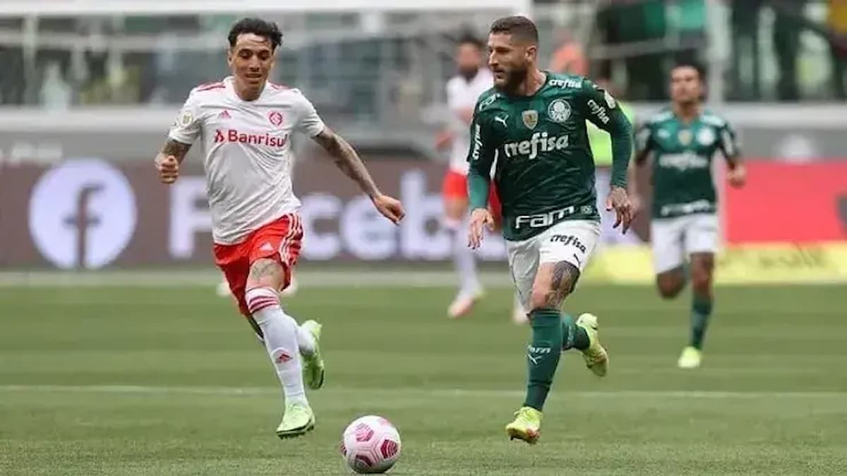 Jogador do Inter e Palmeiras disputando bola durante partida.