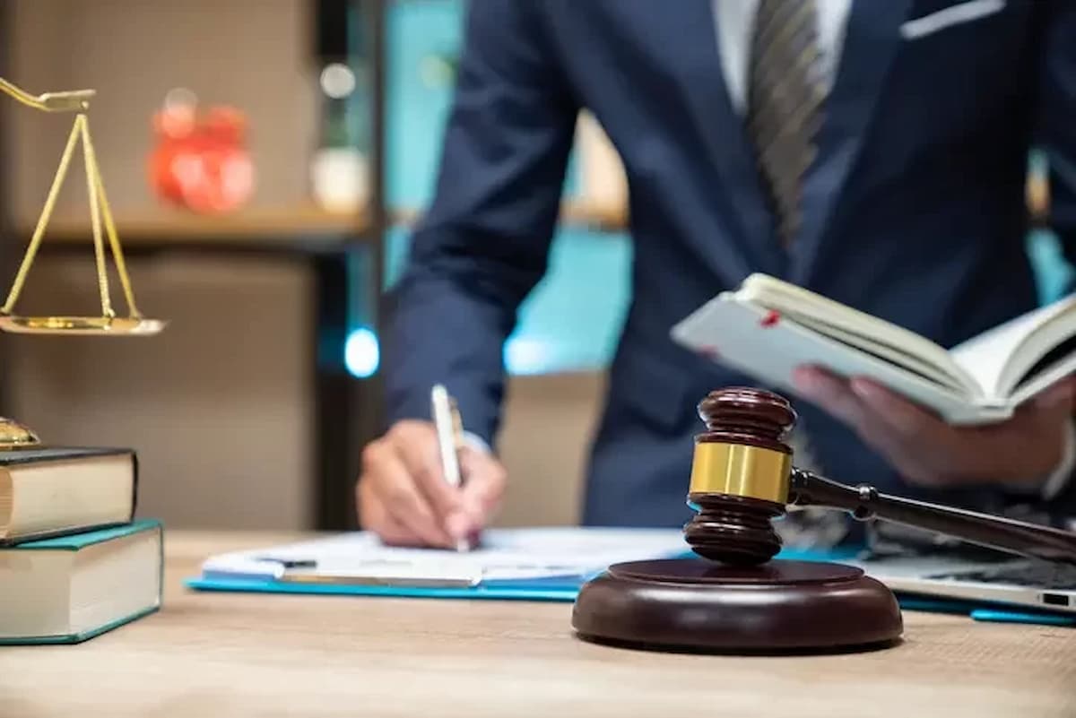 Imagem mostra homem de terno assinando papéis em uma mesa onde está um martelo da justiça, representando o pedido de recuperação judicial.