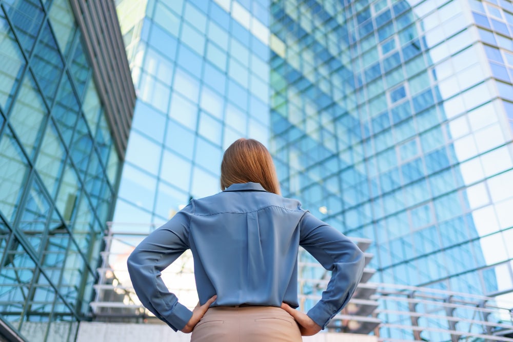 Foto de uma mulher de costas na frente de um prédio espelhado