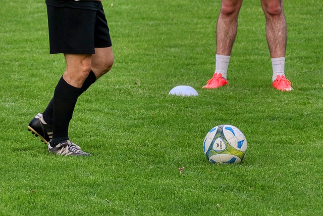 Bola em campo e pernas de jogadores ao fundo