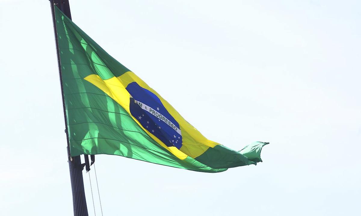 Foto mostra bandeira do Brasil em haste, sob o vento.