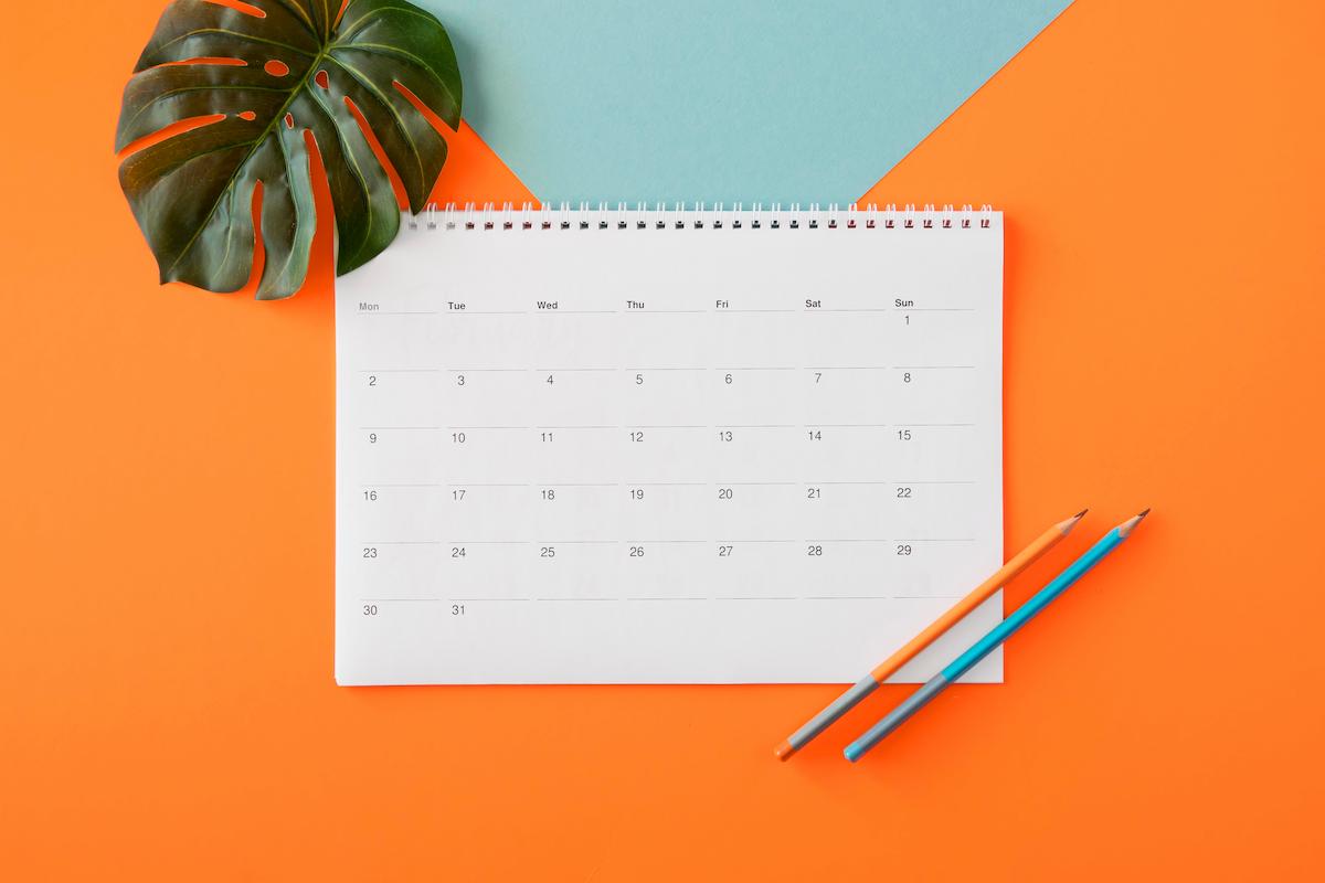 Foto mostra um calendário acima de uma mesa, ao lado de uma planta e dois lápis. Imagem ilustrativa do bom período que será a última semana de julho para pessoas de certos signos.