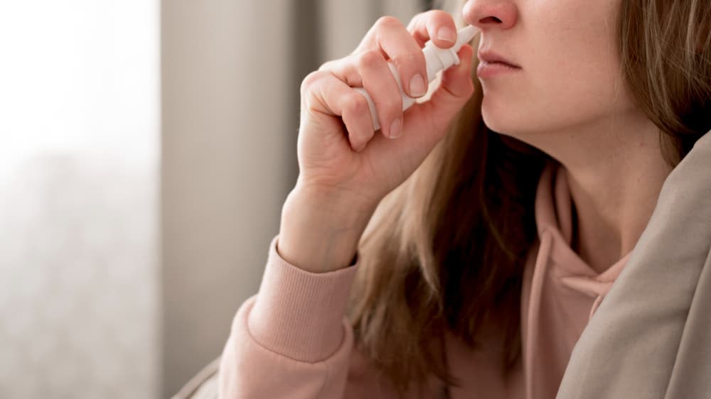 Na imagem, uma mulher aplicando descongestionante nasal