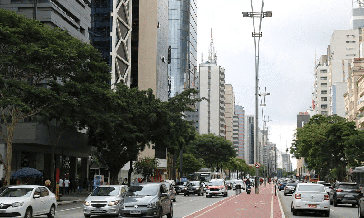 Imagem de veículos transitando em via no Brasil, ilustrativa da cobrança anual do IPVA.