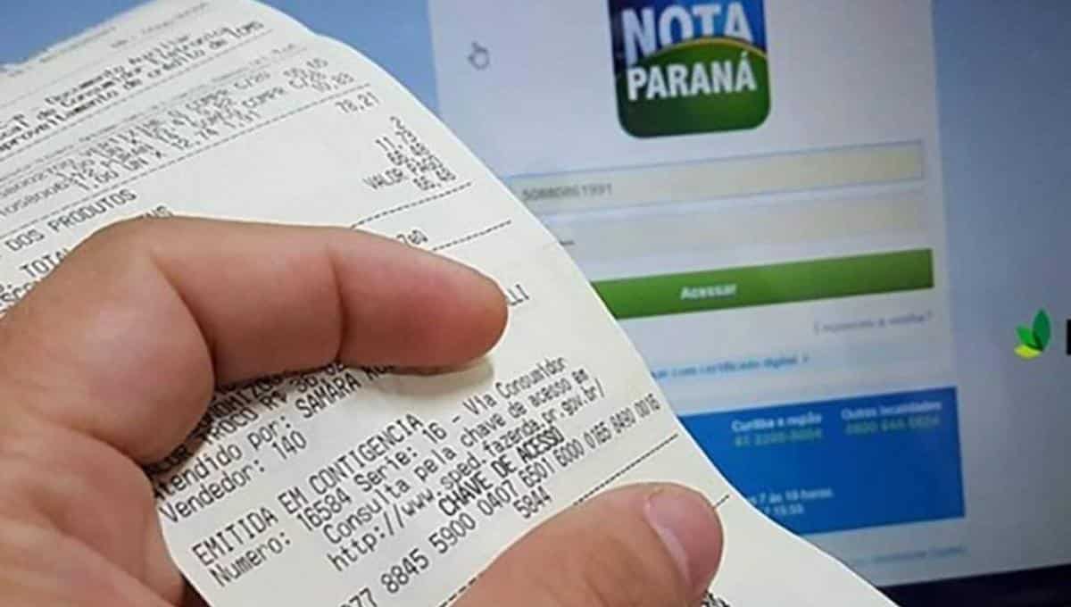 Foto mostra pessoa segurando nota fiscal à frente de uma tela de computador, exibindo a logo do Nota Paraná.