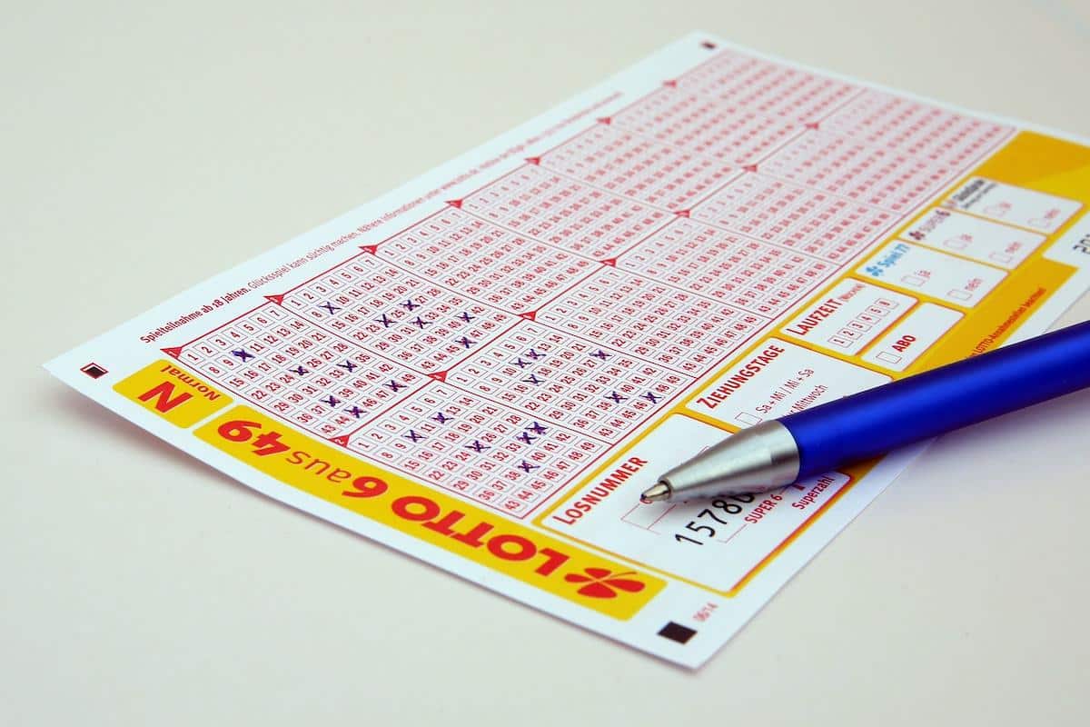 Imagem mostra um bilhete de loteria, junto à uma caneta. Foto ilustrativa das apostas na loteria com números da sorte, associado aos signos.