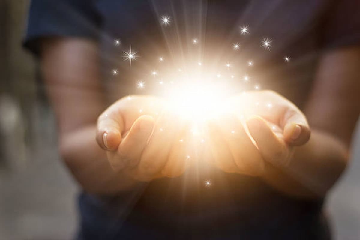Imagem mostra pessoa com mãos abertas recebendo uma luz, que representa um milagre.