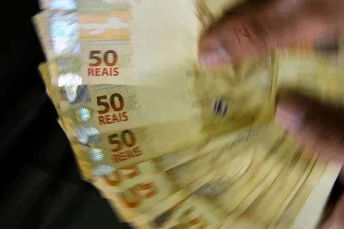 Foto mostra pessoa segurando notas de R$ 50. Imagem ilustrativa do dinheiro que pode chegar para pessoas de signos específicos nos próximos dias.