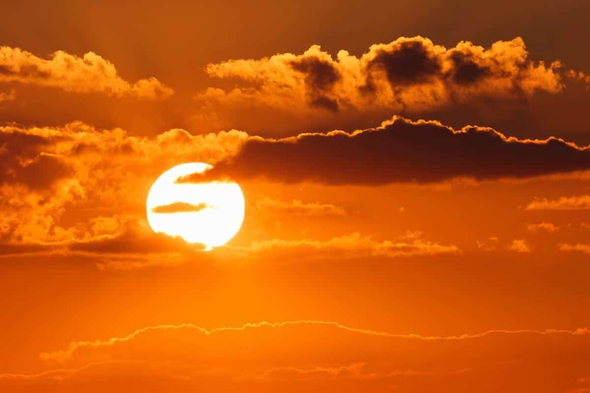 Foto mostra pôr do sol, com o céu alaranjado e algumas nuvens. Imagem ilustrativa da onda de calor que pode chegar ao Brasil em breve.